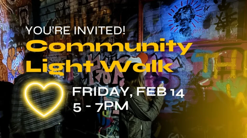 People looking at colorful graffiti on a wall at night. Text reads: Youre Invited! Community Light Walk. Friday, Feb 14, 5–7PM. A glowing heart icon is on the left.